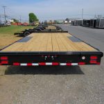 a trailer with a wooden deck is parked on the side of the road .