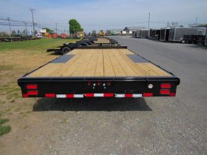 a trailer with a wooden deck is parked on the side of the road .