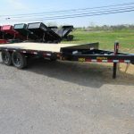 a flatbed trailer is parked on the side of the road .