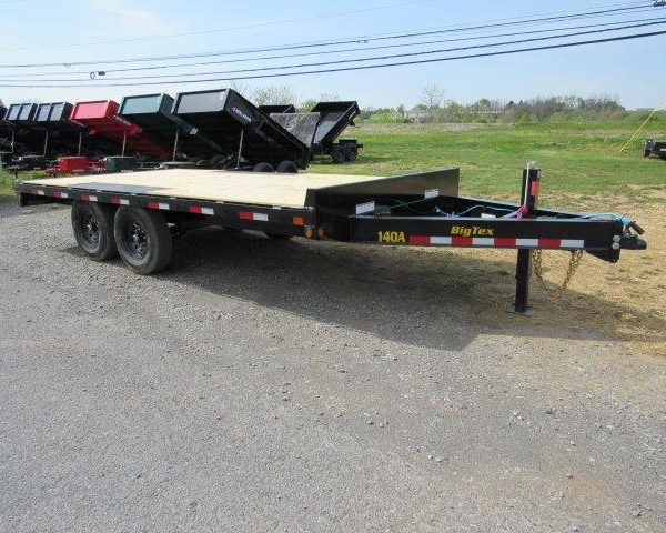 a flatbed trailer is parked on the side of the road .