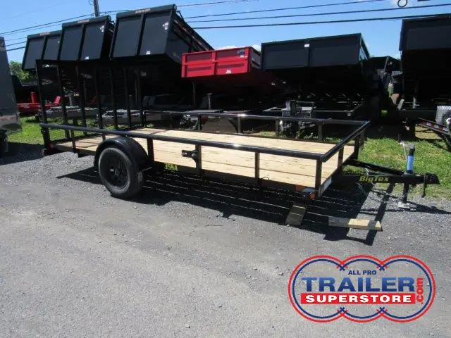 a Big Tex trailer with a wooden deck parked next to a row of dump trailers