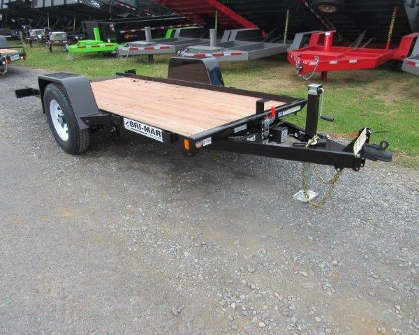 a small trailer with a wooden deck is parked on a gravel road