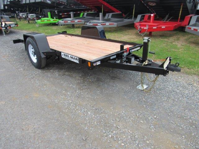 a small trailer with a wooden deck is parked on a gravel road