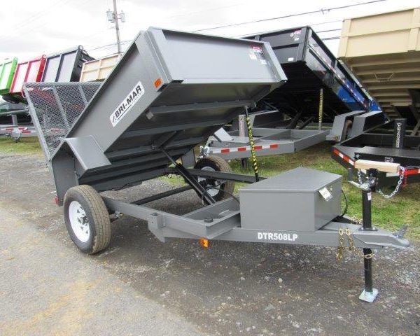 a gray dump trailer is parked on the side of the road .