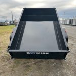 a black dump trailer parked on the side of the road
