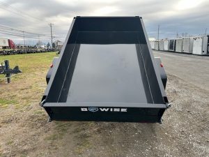 a black dump trailer parked on the side of the road