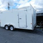 a white trailer is parked on the side of the road .