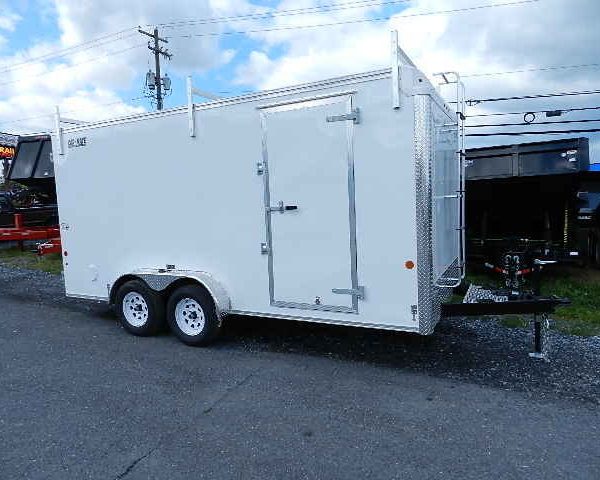 a white trailer is parked on the side of the road .