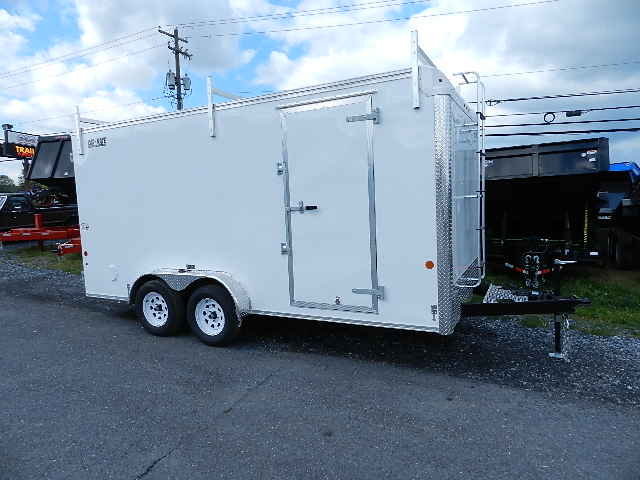 a white trailer is parked on the side of the road .