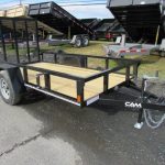 a trailer with a wooden deck is parked on the side of the road .
