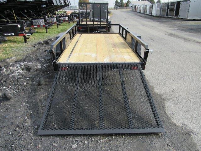 a trailer with a wooden deck and a metal ramp is parked on the side of the road .