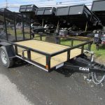 a black trailer with a wooden deck is parked on the side of the road