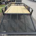 a trailer with a wooden deck and a metal ramp is parked on the side of the road .