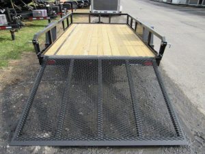 a trailer with a wooden deck and a metal ramp is parked on the side of the road .