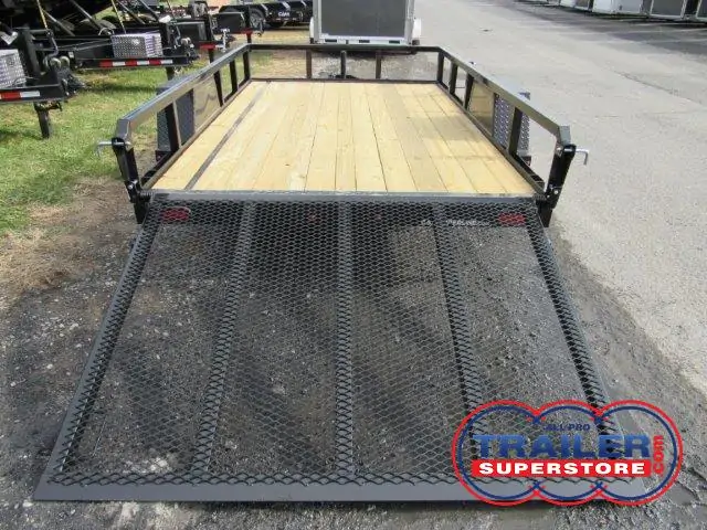 a trailer with a wooden deck and a metal ramp is parked on the side of the road .