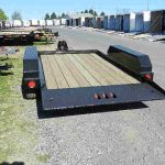 a CAM Superline trailer with a wooden deck parked in a gravel lot