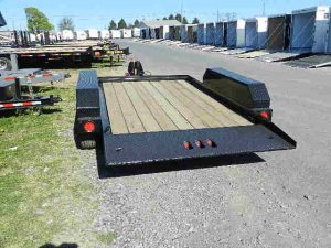 a CAM Superline trailer with a wooden deck parked in a gravel lot