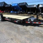 a CAM Superline trailer with a wooden deck parked next to a row of dump trailers