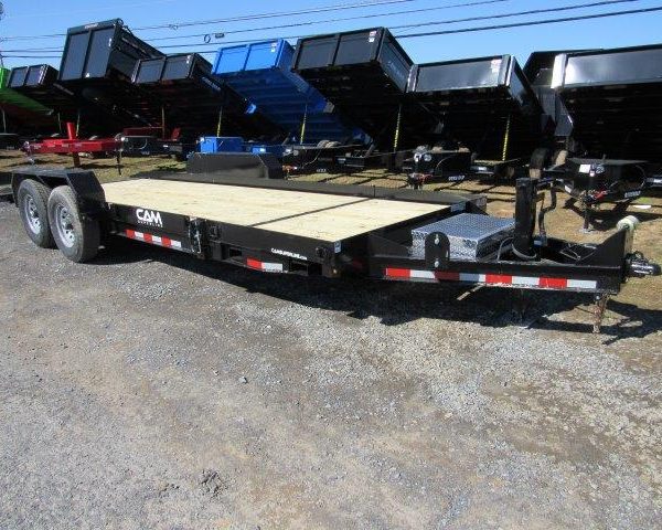 a CAM Superline trailer with a wooden deck parked next to a row of dump trailers
