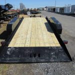 a trailer with a wooden deck is parked on the side of the road .
