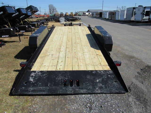 a trailer with a wooden deck is parked on the side of the road .