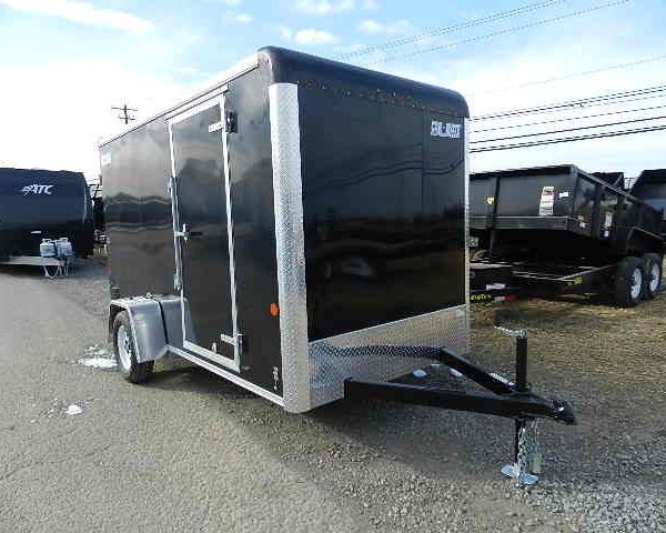 a black trailer is parked on the side of the road next to a dumpster .