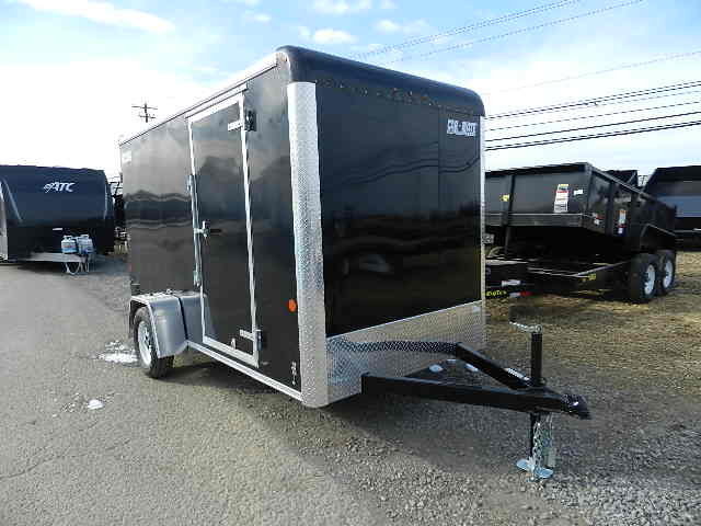 a black trailer is parked on the side of the road next to a dumpster .