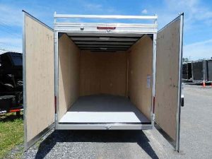 the back of an empty trailer with its doors open .