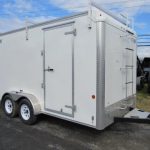 a white trailer with a ladder on the front is parked in a parking lot