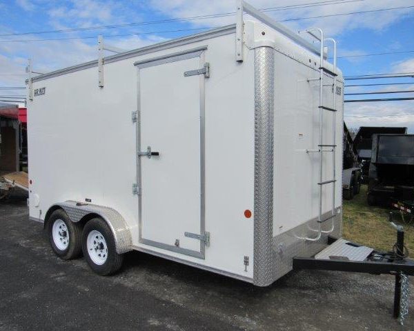 a white trailer with a ladder on the front is parked in a parking lot