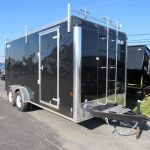 a black trailer with a ladder attached to it is parked on the side of the road .