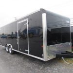 a black trailer parked in a gravel lot