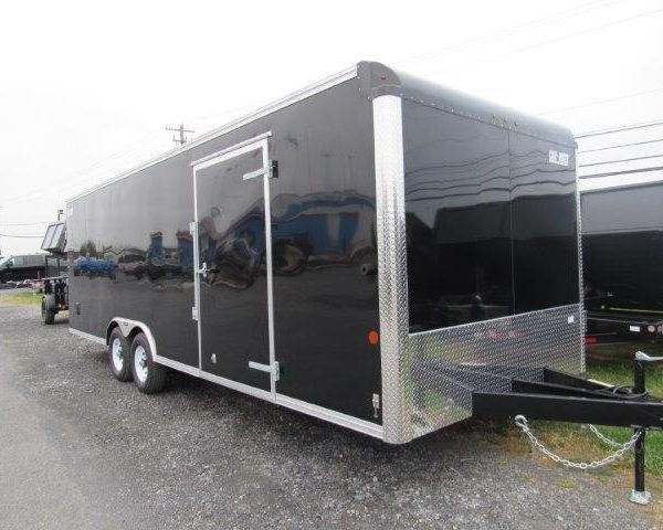 a black trailer parked in a gravel lot