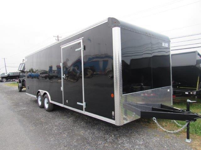 a black trailer parked in a gravel lot