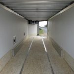 the inside of an empty trailer with the door open .