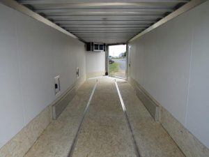 the inside of an empty trailer with the door open .