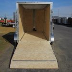 a cargo trailer with the door open is parked on the side of the road .