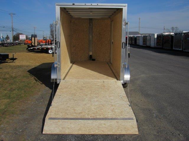 a cargo trailer with the door open is parked on the side of the road .