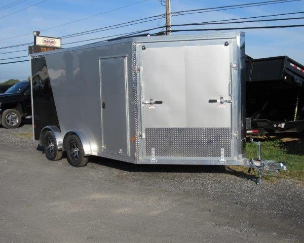 a silver trailer is parked on the side of a road next to a truck