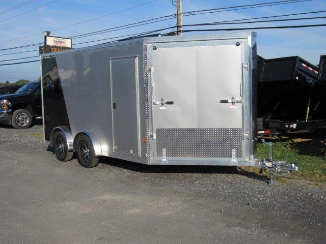 a silver trailer is parked on the side of a road next to a truck