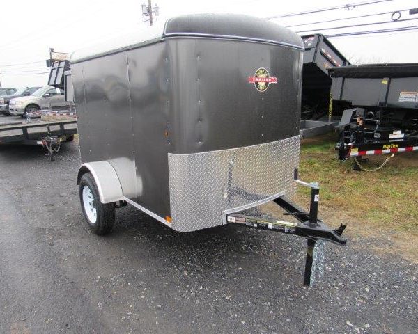 a black trailer is parked on the side of the road next to a dump trailers .