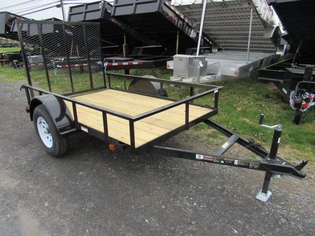a small trailer with a wooden deck is parked on the side of the road .