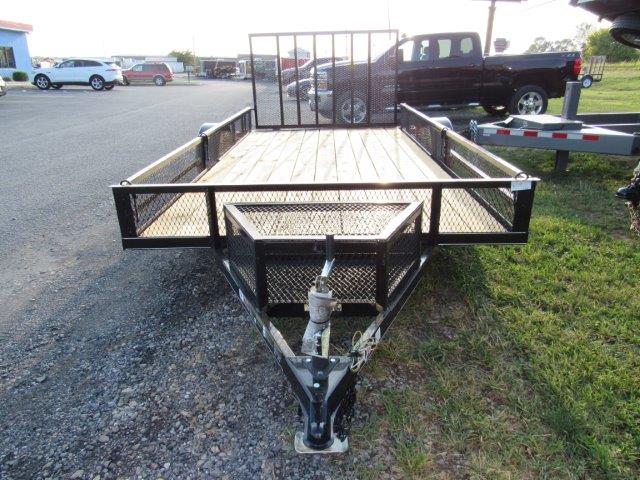 a Carry On trailer parked in a gravel lot next to a truck