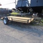 a trailer with a wooden deck is parked on the side of the road next to a dump trailers