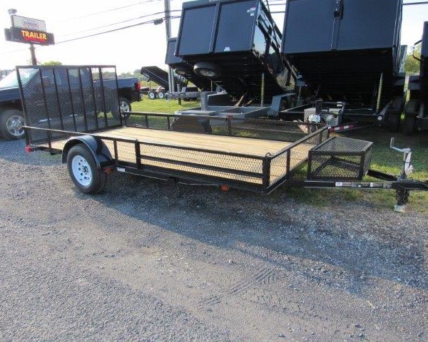a trailer with a wooden deck is parked on the side of the road next to a dump trailers