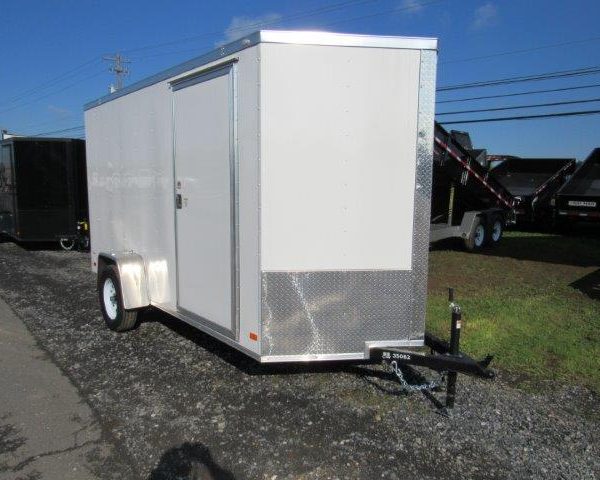 a white trailer is parked on the side of the road .