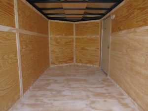 an empty trailer with wooden walls and a door .