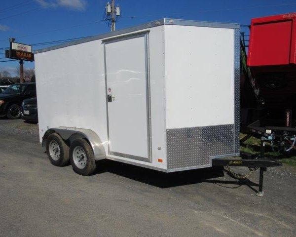 a white trailer is parked on the side of the road .