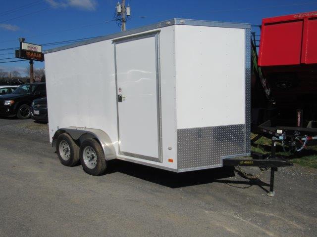 a white trailer is parked on the side of the road .