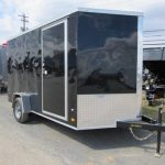 a black and silver trailer is parked in a parking lot .